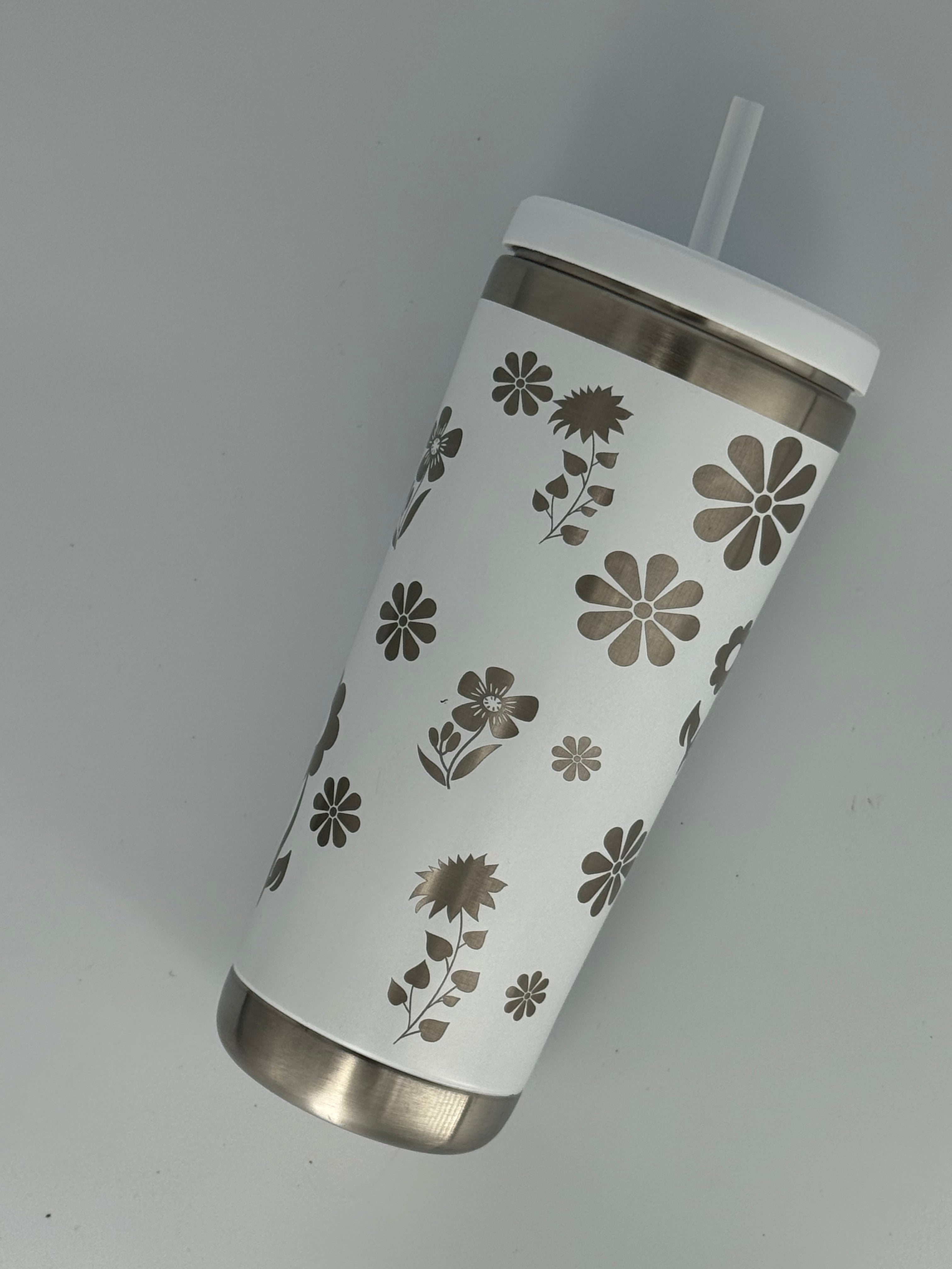 White stainless steel tumbler with laser-engraved floral design featuring daisies, sunflowers, and wildflowers, with lid and straw