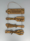 Wooden kitchen utensil wall hanging with laser-engraved text reading Kitchen brings family together